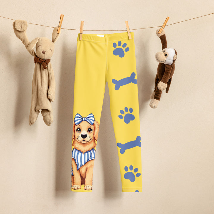 Puppy & Bones Girls Leggings, yellow background with a golden retriever puppy wearing a blue and white striped outfit and a matching blue and white bow on the head on one leg, and blue paw prints and blue bones running down the other leg, front view on hanger
