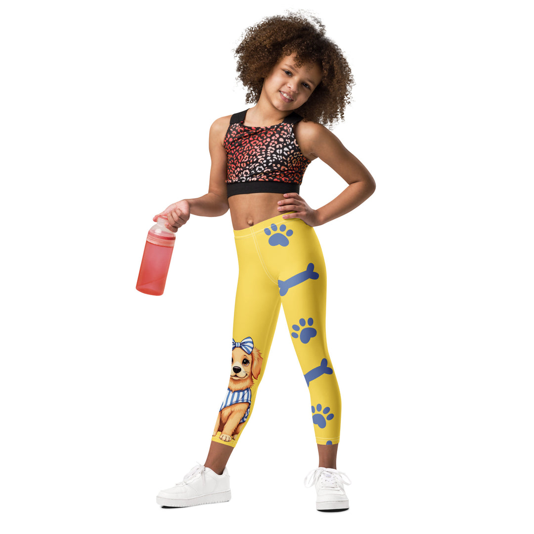  Puppy & Bones Girls Leggings, yellow background with a golden retriever puppy wearing a blue and white striped outfit and a matching blue and white bow on the head on one leg, and blue paw prints and blue bones running down the other leg, relaxed front pose on model