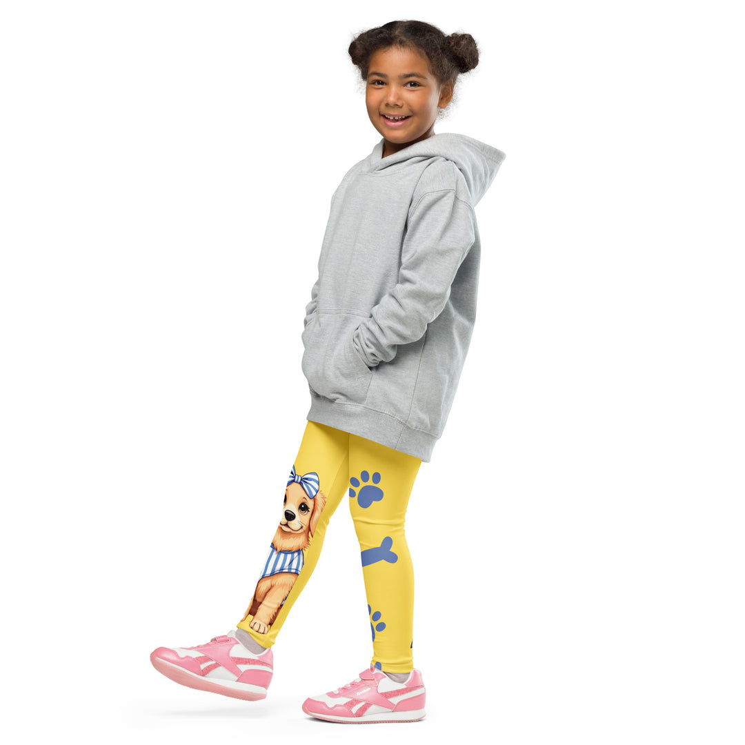 Puppy & Bones Girls Leggings, yellow background with a golden retriever puppy wearing a blue and white striped outfit and a matching blue and white bow on the head on one leg, and blue paw prints and blue bones running down the other leg, side view with one leg lifted and extended on model
