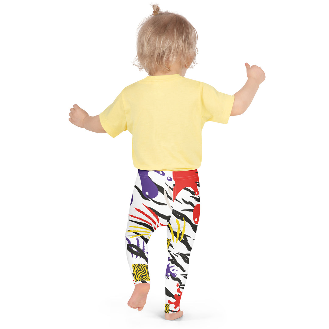 Raccoon Bandit Glow Girls Leggings, white base with splash-like spots in red, purple, and yellow, gray raccoon head, and wavy black stripes, back angle with relaxed pose on model