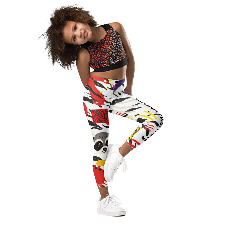 Raccoon Bandit Glow Girls Leggings, white base with splash-like spots in red, purple, and yellow, gray raccoon head, and wavy black stripes, front view with one leg lifted and bent on model-with a visible 'Leona Fashion' text on the design