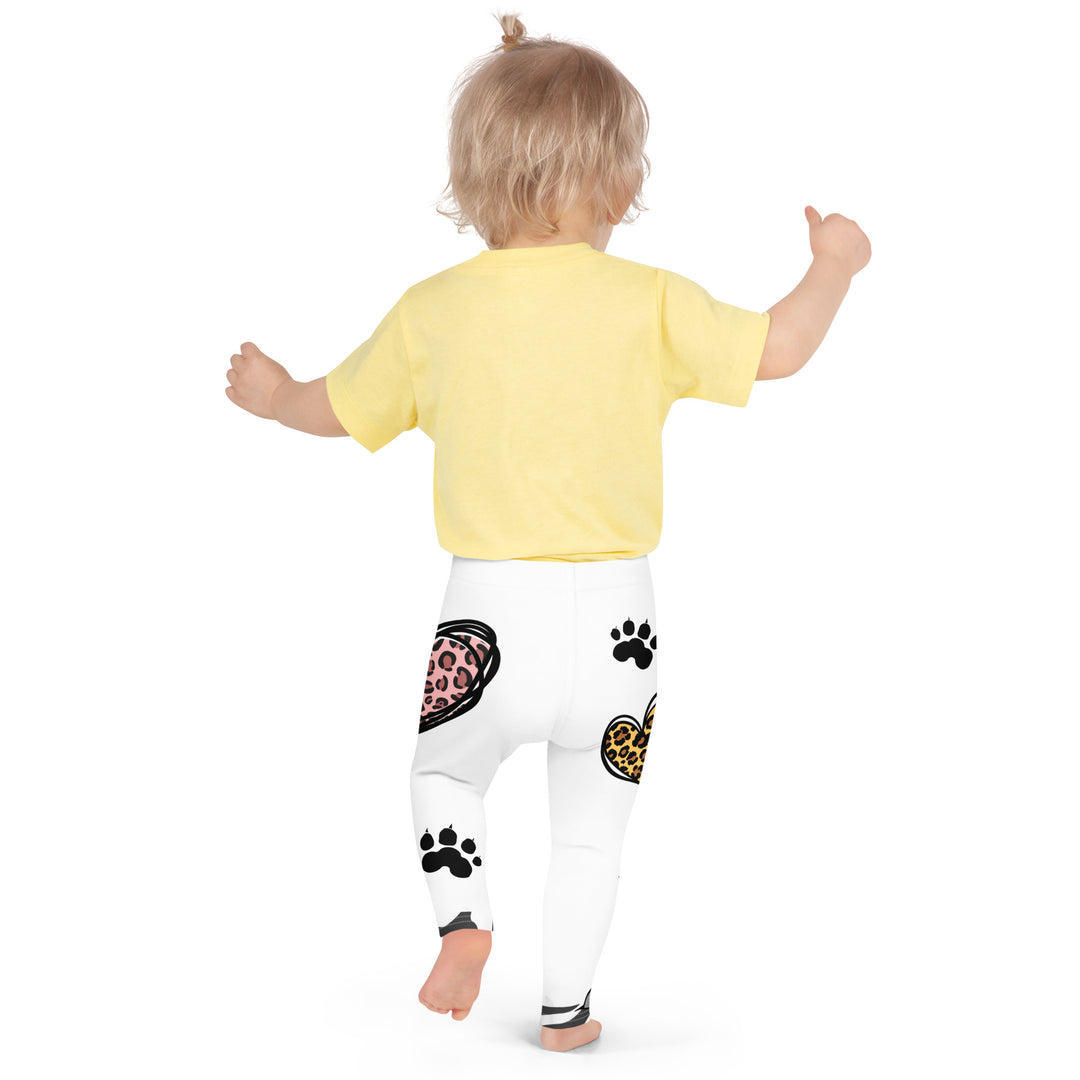 Raccoon Love Girls Leggings, white background with gray raccoon blowing a pink bubble gum sitting on a rock, pink tiger-striped heart, claws, and animal paw details, back angle with relaxed pose on model