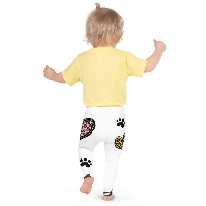 Raccoon Love Girls Leggings, white background with gray raccoon blowing a pink bubble gum sitting on a rock, pink tiger-striped heart, claws, and animal paw details, back angle with relaxed pose on model