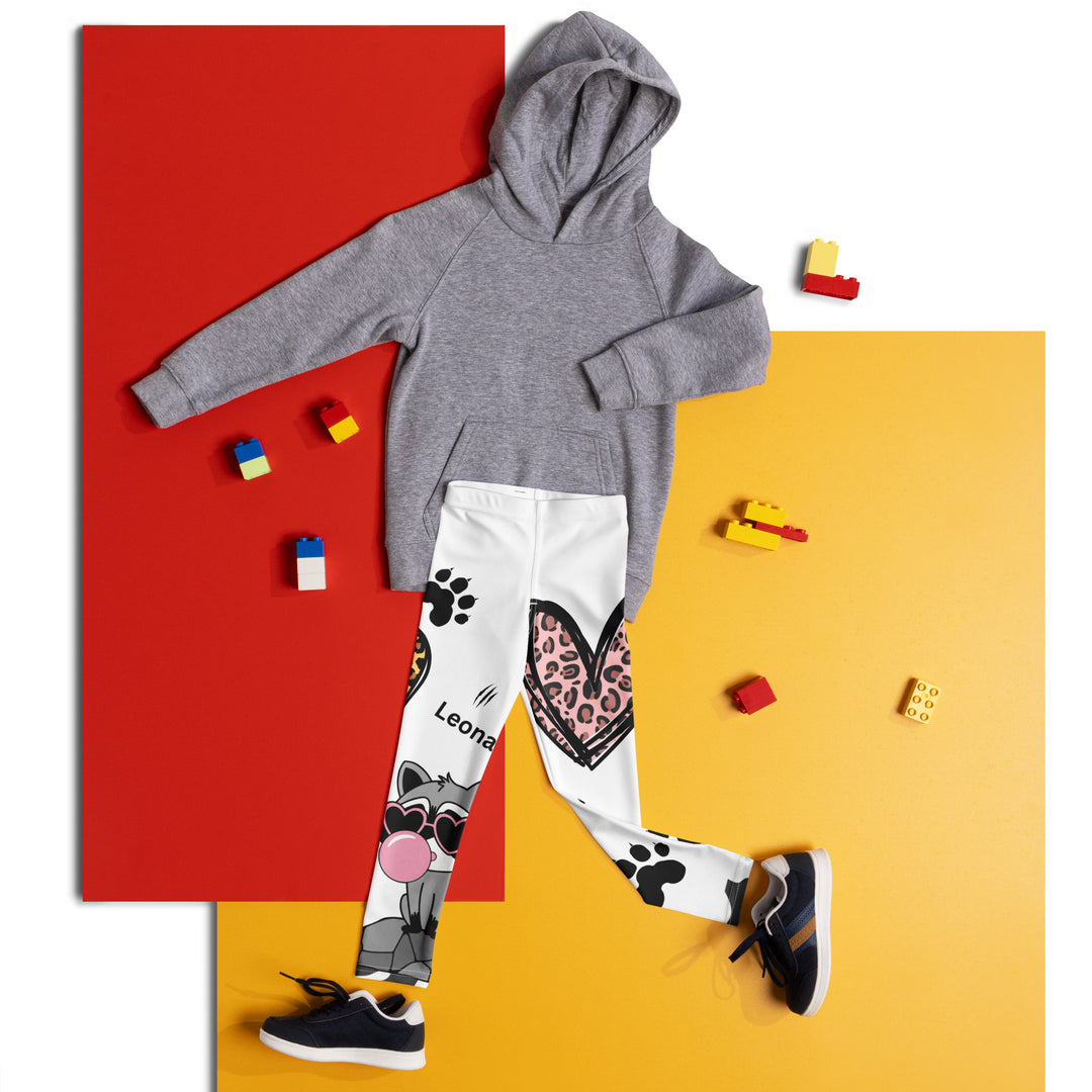  Raccoon Love Girls Leggings, white background with gray raccoon blowing a pink bubble gum sitting on a rock, pink tiger-striped heart, claws, and animal paw details, front view laid flat on floor-with a visible 'Leona Fashion' text on the design