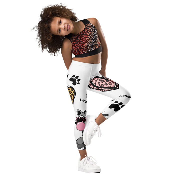  Raccoon Love Girls Leggings, white background with gray raccoon blowing a pink bubble gum sitting on a rock, pink tiger-striped heart, claws, and animal paw details, front view with one leg lifted and bent on model-with a visible 'Leona Fashion' text on the design