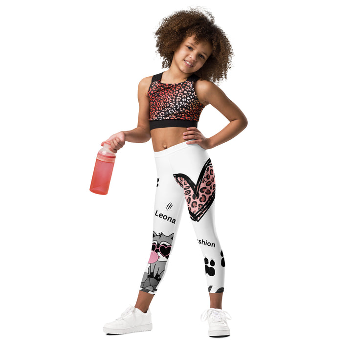  Raccoon Love Girls Leggings, white background with gray raccoon blowing a pink bubble gum sitting on a rock, pink tiger-striped heart, claws, and animal paw details, relaxed front pose on model-with a visible 'Leona Fashion' text on the design
