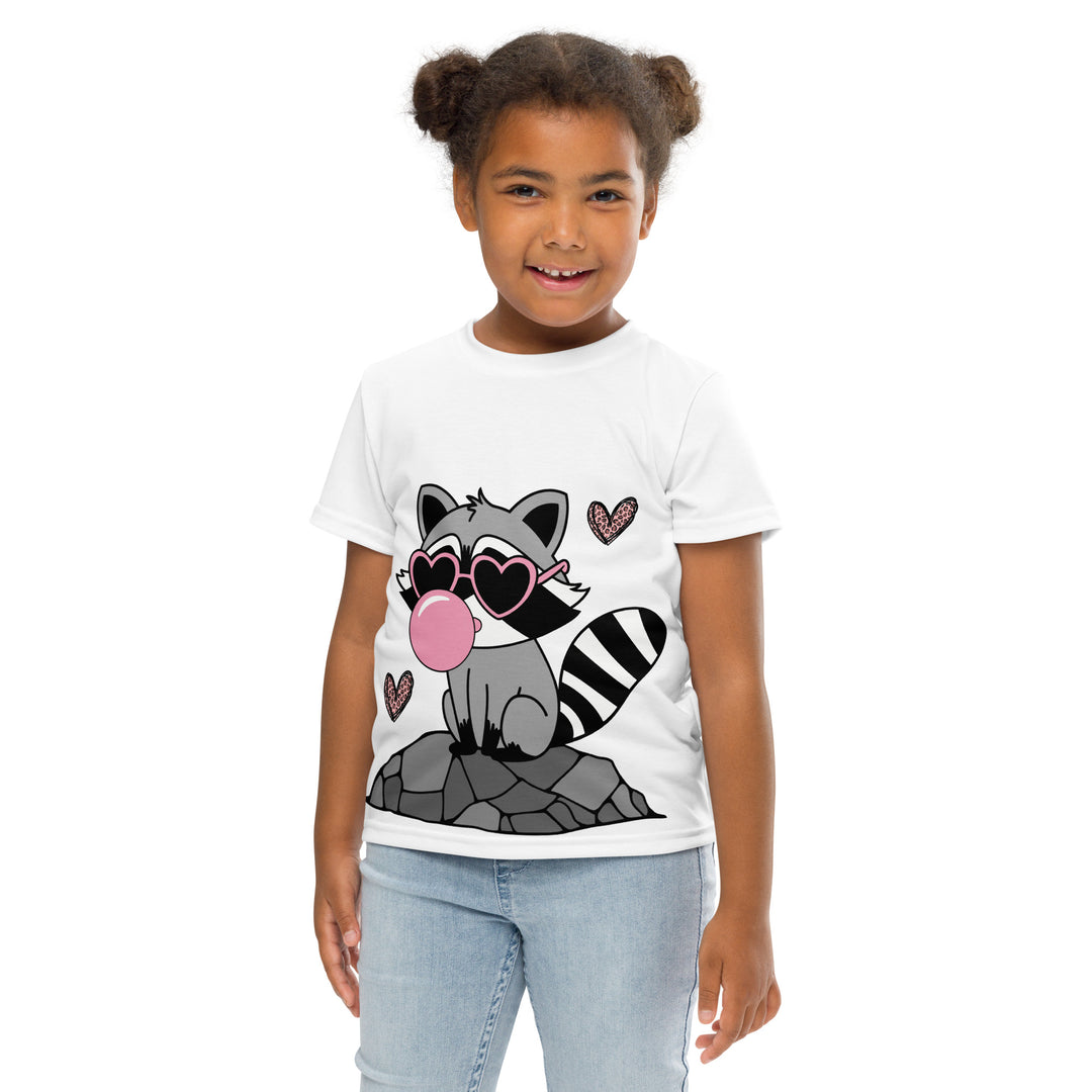 Raccoon Love Girls T-shirt – front close-up pose with arms extended on model, white with gray raccoon standing on a rock blowing a pink bubble gum, wearing pink heart-shaped sunglasses, surrounded by pink tiger-striped hearts