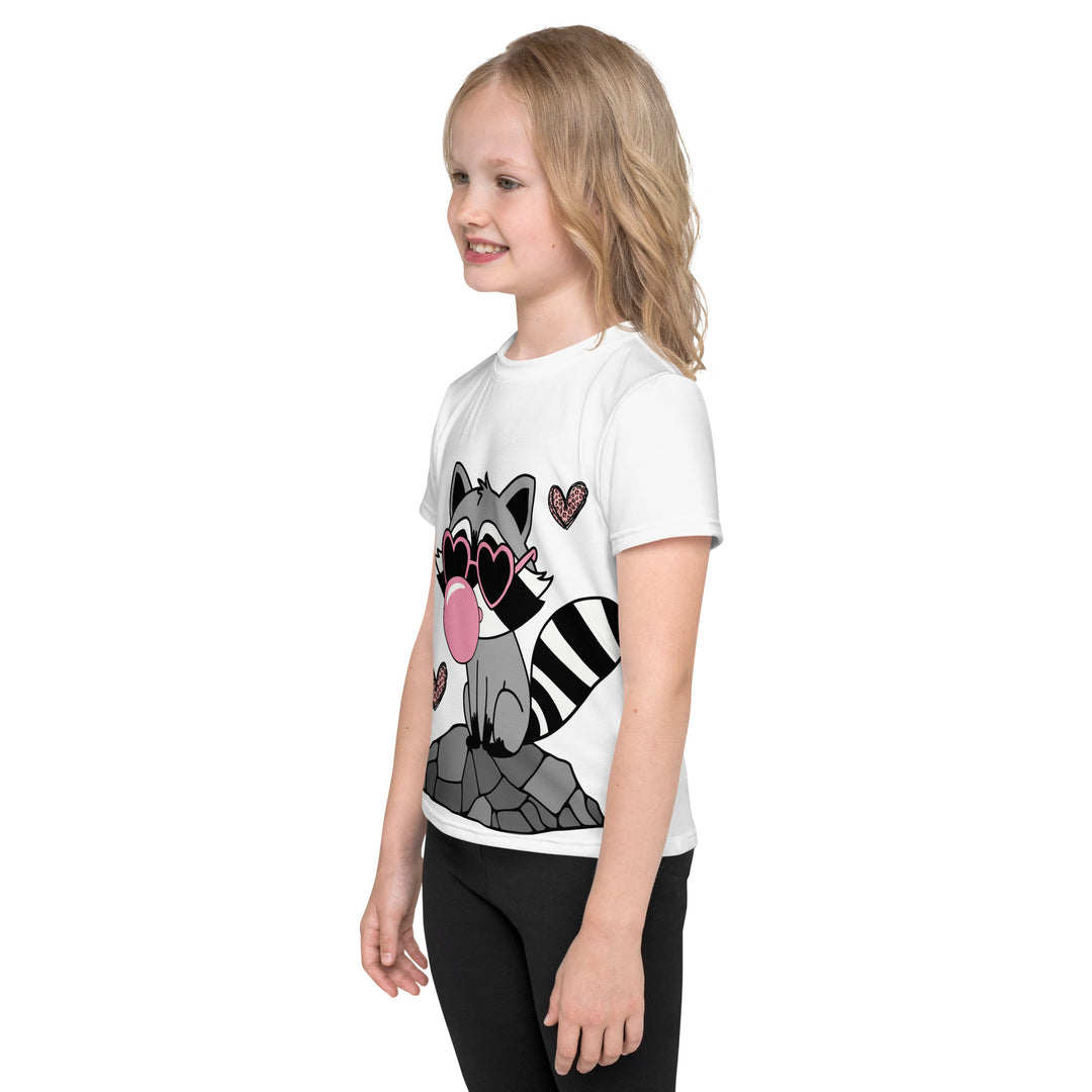  Raccoon Love Girls T-shirt – left side view on model, white with gray raccoon standing on a rock blowing a pink bubble gum, wearing pink heart-shaped sunglasses, surrounded by pink tiger-striped hearts