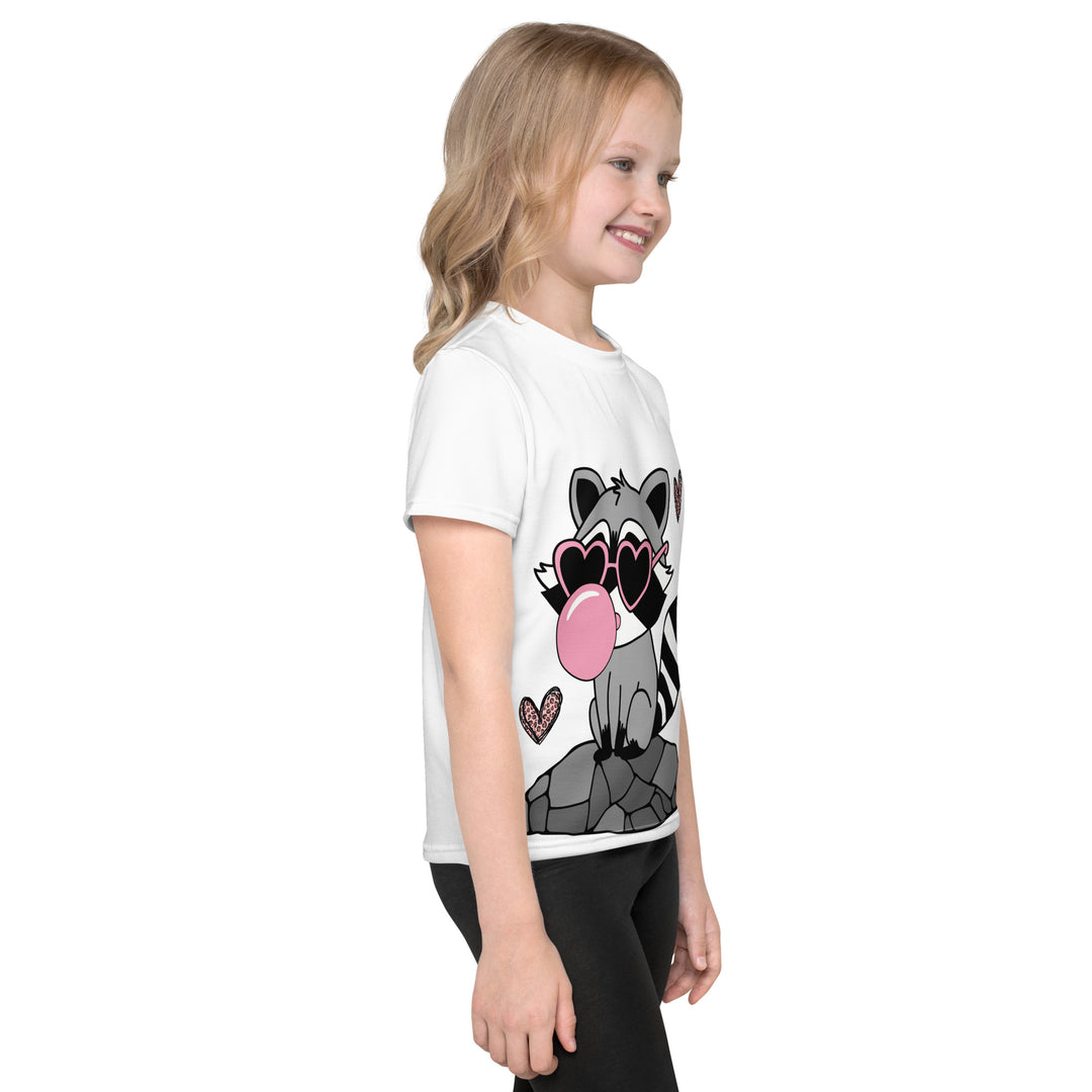  Raccoon Love Girls T-shirt – right side view on model, white with gray raccoon standing on a rock blowing a pink bubble gum, wearing pink heart-shaped sunglasses, surrounded by pink tiger-striped hearts