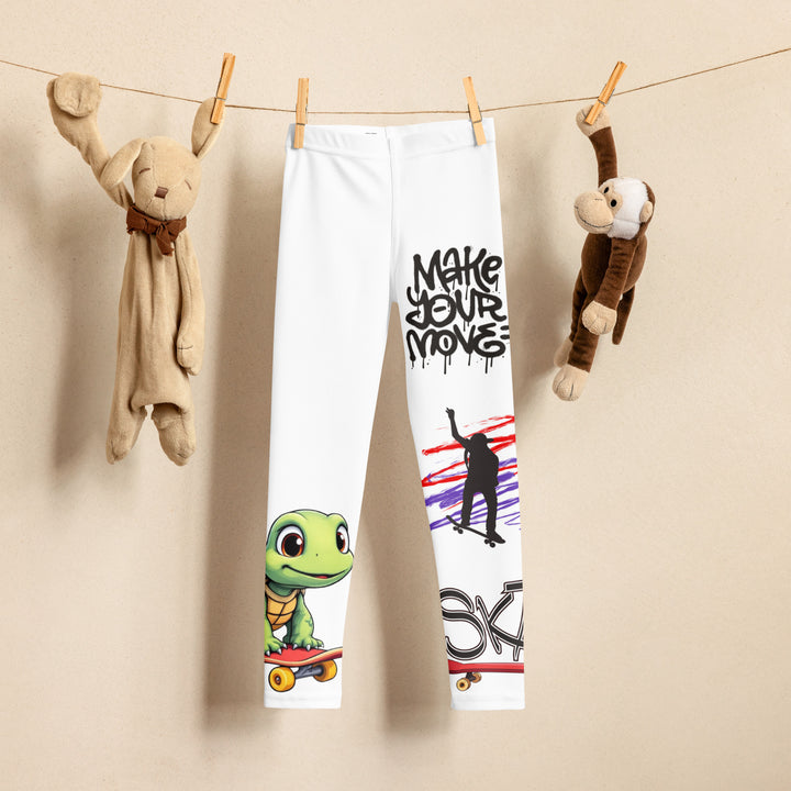 Skater Turtle Girls Leggings, white background with a green turtle riding a skateboard on one leg, black "MAKE YOUR MOVE" text and black skater silhouette with pink and purple motion lines on the other leg, and a skateboard with "skate" text at the bottom of the leg, front view on hanger