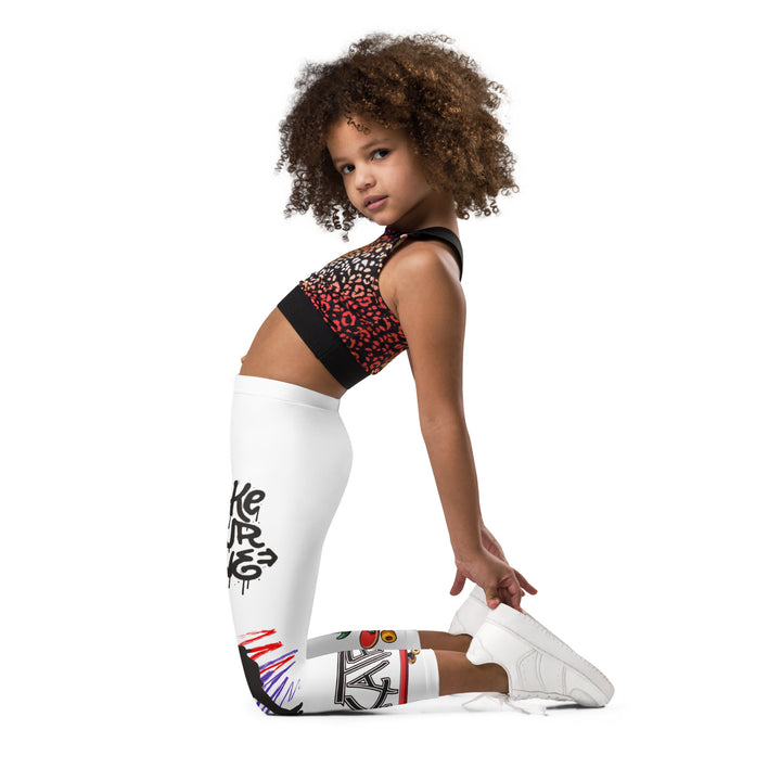 Skater Turtle Girls Leggings, white background with a green turtle riding a skateboard on one leg, black "MAKE YOUR MOVE" text and black skater silhouette with pink and purple motion lines on the other leg, and a skateboard with "skate" text at the bottom of the leg, left side view kneeling on model