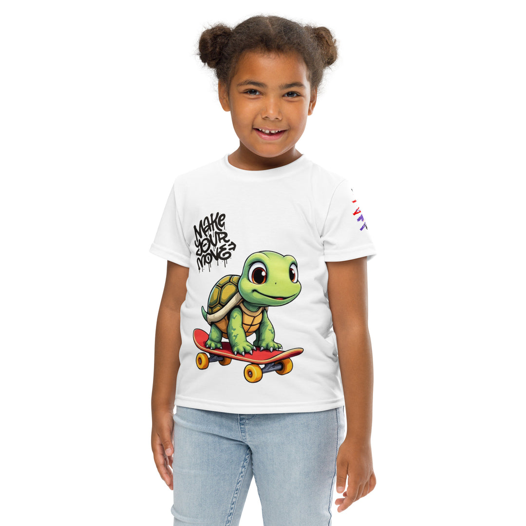 Skater Turtle Girls T-shirt, white background with a green turtle on a skateboard and black "MAKE YOUR MOVE" text on the front, black skater silhouette with pink and purple motion lines on the left sleeve, and a skateboard with "SKATE" text at the bottom back of the shirt, front pose with arms at sides on model
