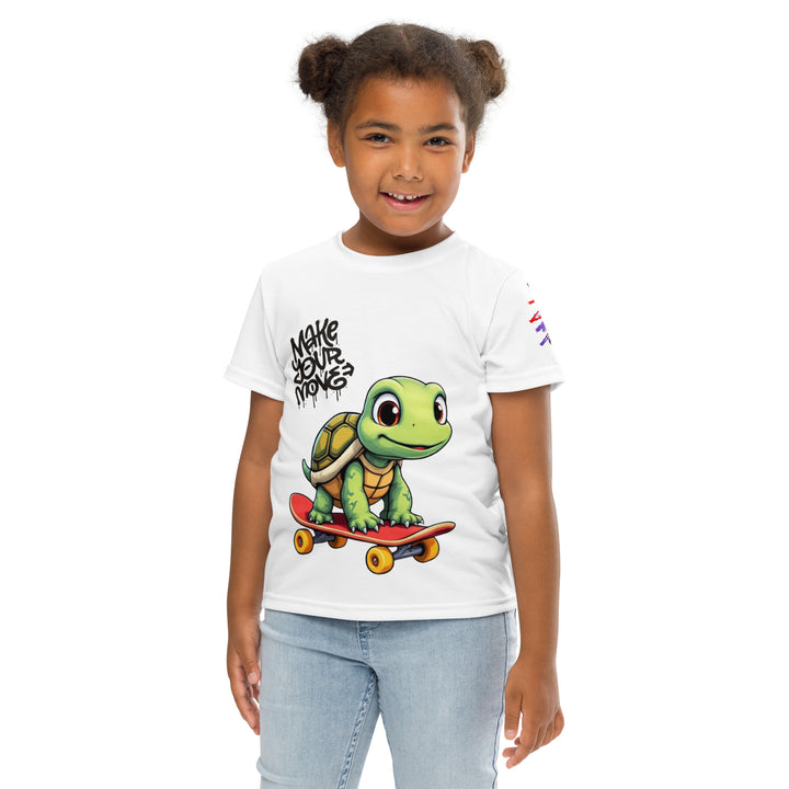 Skater Turtle Girls T-shirt, white background with a green turtle on a skateboard and black "MAKE YOUR MOVE" text on the front, black skater silhouette with pink and purple motion lines on the left sleeve, and a skateboard with "SKATE" text at the bottom back of the shirt, front pose with arms at sides on model