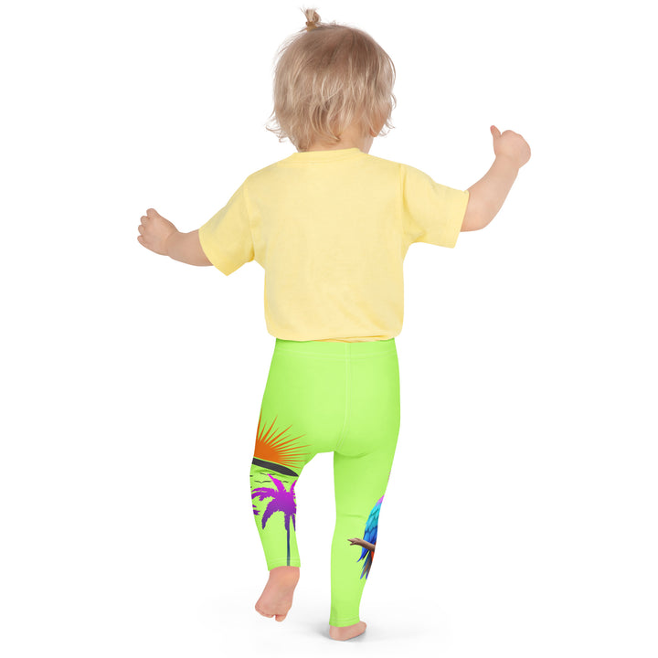  Sunset Parrot Girls Leggings, neon green background with an orange, blue, and purple parrot standing on a branch on one leg, and an orange sunset with flying birds and a purple palm tree on the other leg, back pose on model