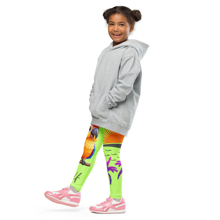 Sunset Parrot Girls Leggings, neon green background with an orange, blue, and purple parrot standing on a branch on one leg, and an orange sunset with flying birds and a purple palm tree on the other leg, side view with one leg lifted and extended on model