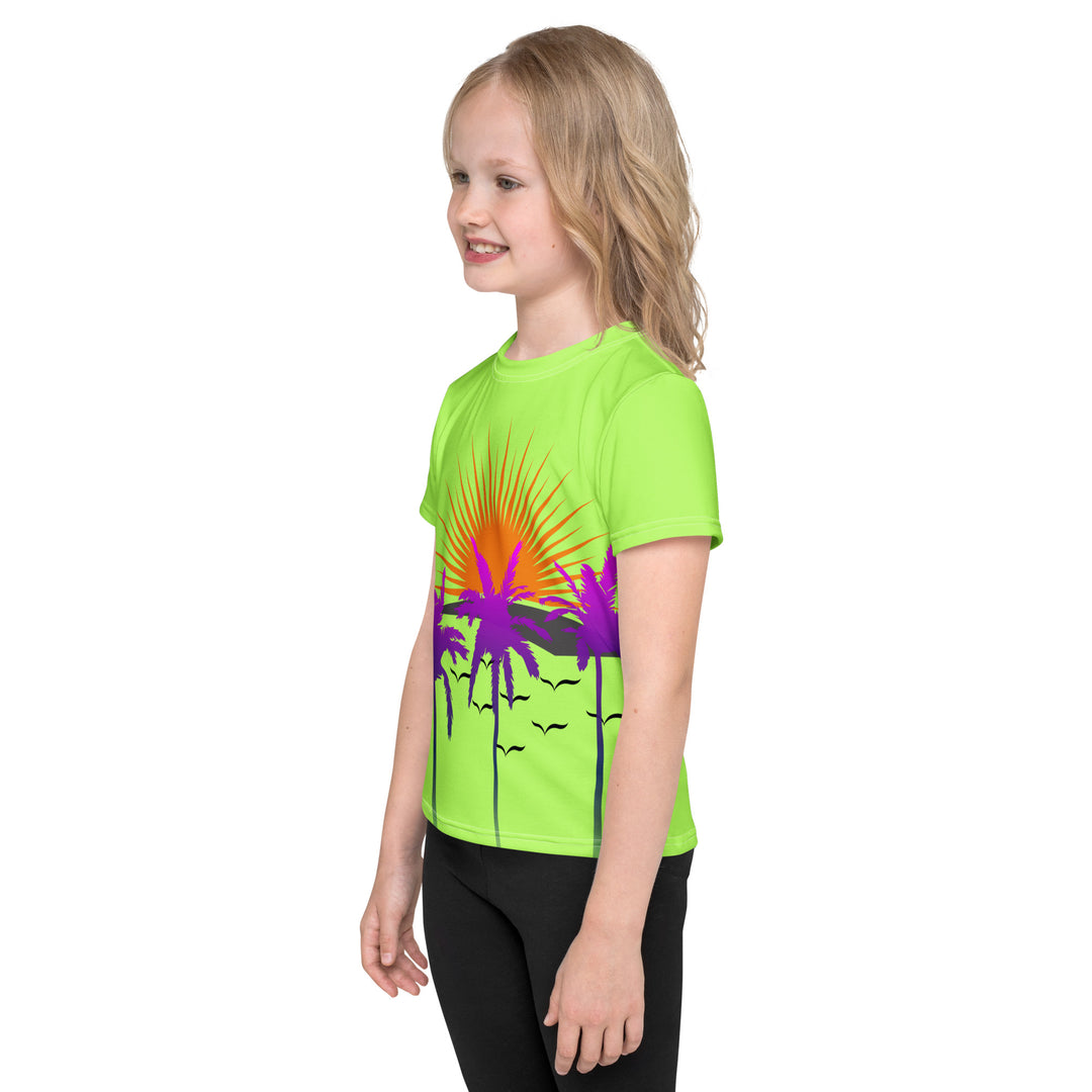 Sunset Parrot Girls T-shirt, neon green background with an orange sunset, flying birds, and three purple palm trees on the front, and an orange, purple, and blue parrot standing on a branch on the back, left side view on model