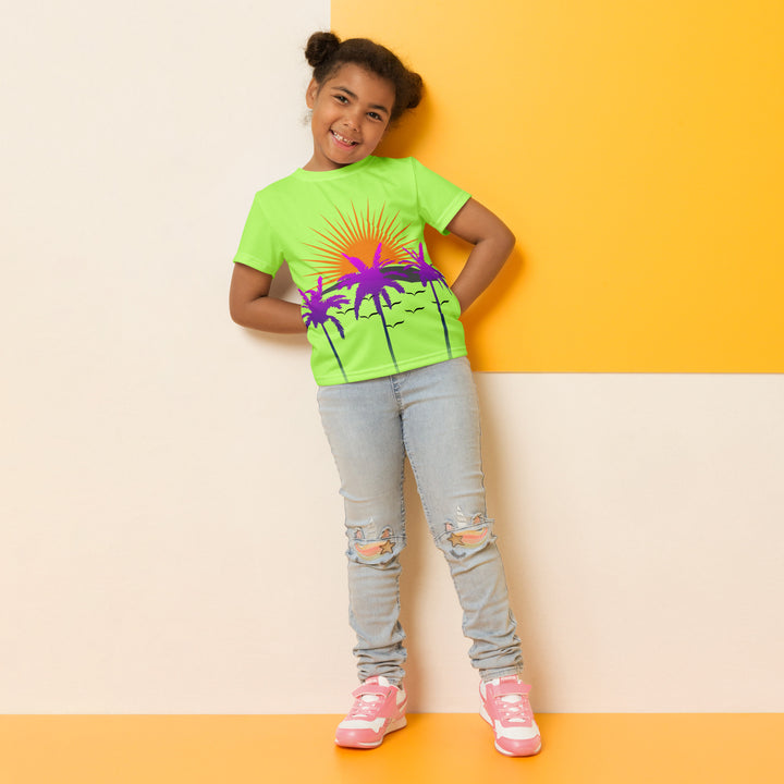  Sunset Parrot Girls T-shirt, neon green background with an orange sunset, flying birds, and three purple palm trees on the front, and an orange, purple, and blue parrot standing on a branch on the back, relaxed front pose on model