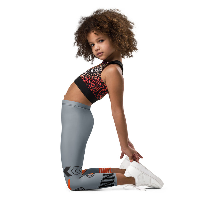 Track Runner Kangaroo Girls Leggings, dark gray background with a sporty kangaroo running on an orange track on one leg, "get ready" text in black and orange above, and an orange and black medal with "runner" text in the lower corner on the other leg, left side view kneeling on model