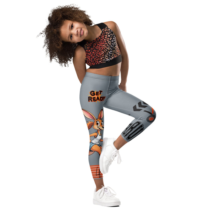  Track Runner Kangaroo Girls Leggings, dark gray background with a sporty kangaroo running on an orange track on one leg, "get ready" text in black and orange above, and an orange and black medal with "runner" text in the lower corner on the other leg, side view with one leg lifted and bent on model