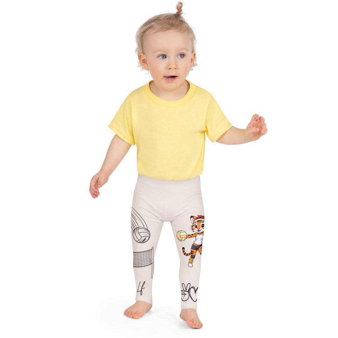Volley Queen Tiger Girls Leggings, beige background with one leg featuring a sporty dressed tiger holding a volleyball, and the other leg with a volleyball net and a ball leaving a motion trail, front close-up view on model