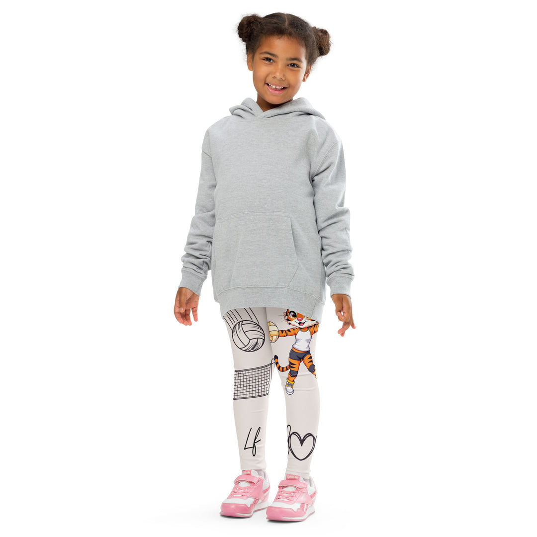Volley Queen Tiger Girls Leggings, beige background with one leg featuring a sporty dressed tiger holding a volleyball, and the other leg with a volleyball net and a ball leaving a motion trail, front pose with arms at sides on model