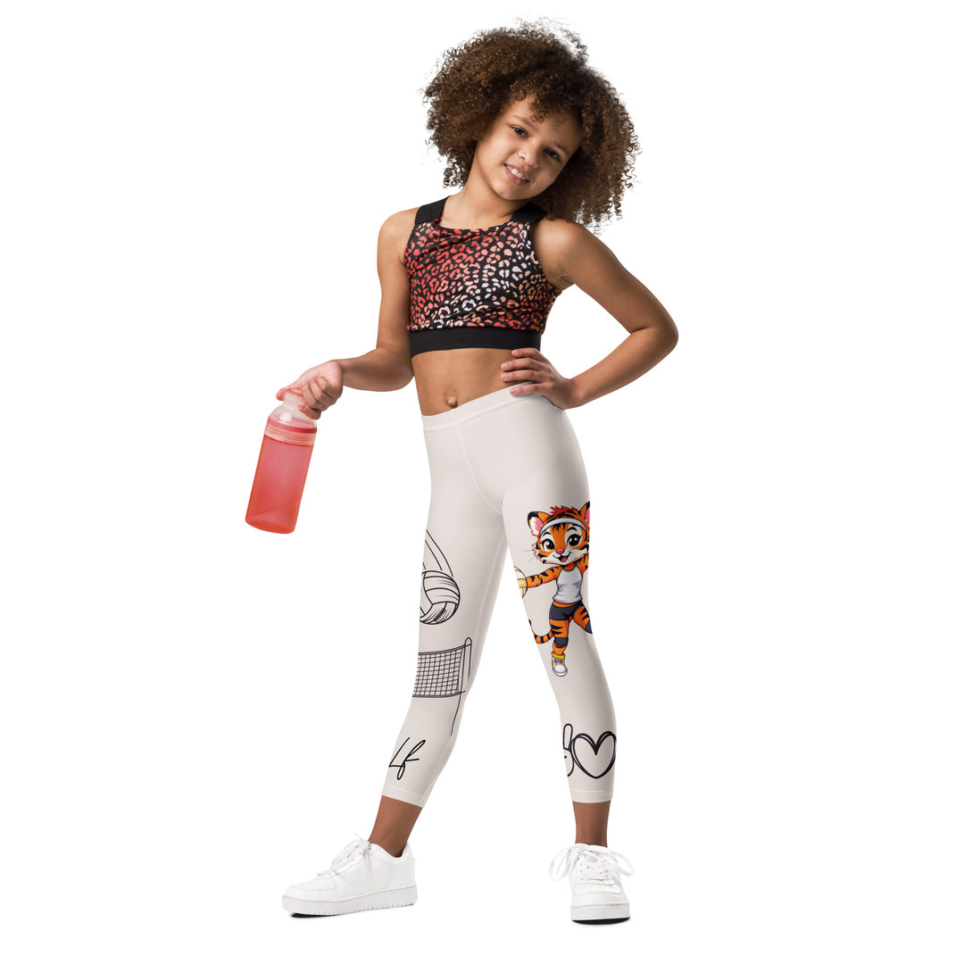  Volley Queen Tiger Girls Leggings, beige background with one leg featuring a sporty dressed tiger holding a volleyball, and the other leg with a volleyball net and a ball leaving a motion trail, front view on model