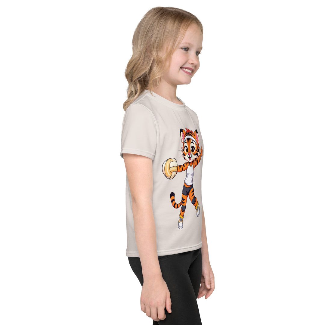 Volley Queen Tiger Girls T-shirt, beige background with a sporty dressed tiger holding a volleyball on the front, a heart, volleyball, and peace sign on the left sleeve, and a volleyball net with a ball leaving a motion trail on the back, right side view on model