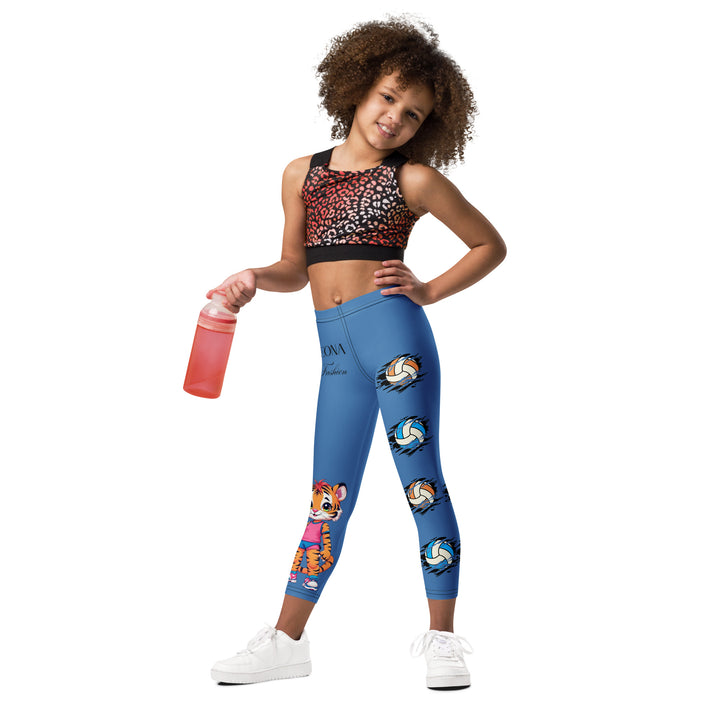  Volleyball Tiger Girls Leggings, blue background with a sporty dressed tiger holding a volleyball on one leg, and colorful glowing volleyballs on the other leg, front view on model-with a visible 'Leona Fashion' text on the design