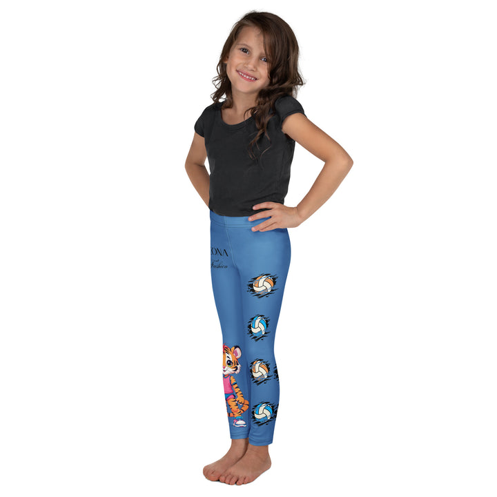 Volleyball Tiger Girls Leggings, blue background with a sporty dressed tiger holding a volleyball on one leg, and colorful glowing volleyballs on the other leg, left side view on model
