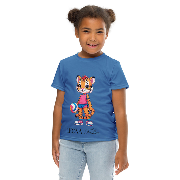 Volleyball Tiger Girls T-shirt, blue background with a sporty dressed tiger holding a volleyball on the front, and colorful glowing volleyballs on the back, front pose with arms at sides on model-with a visible 'Leona Fashion' text on the design