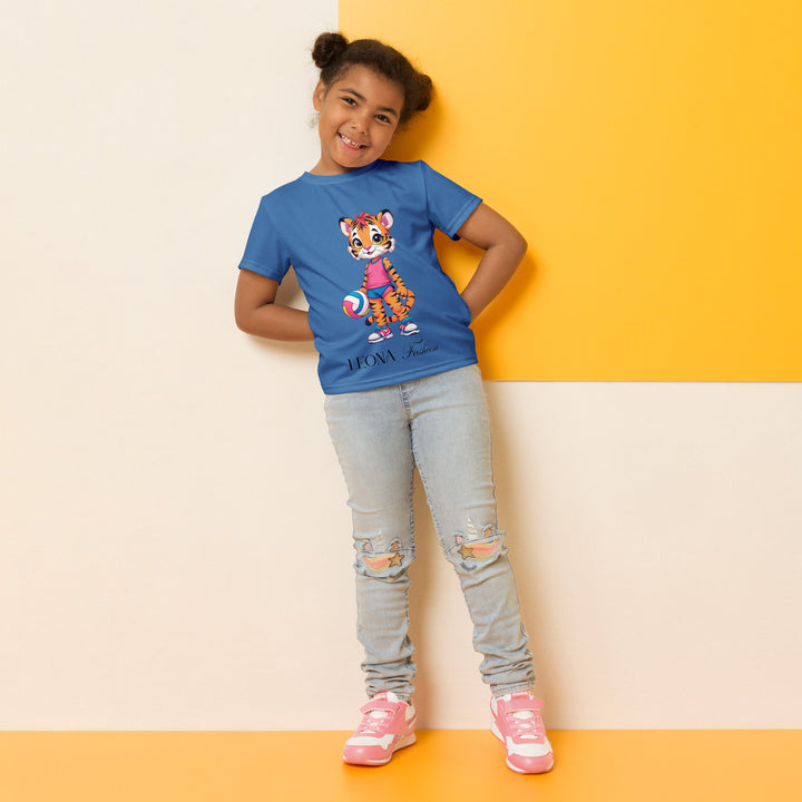 Volleyball Tiger Girls T-shirt, blue background with a sporty dressed tiger holding a volleyball on the front, and colorful glowing volleyballs on the back, relaxed front pose on model-with a visible 'Leona Fashion' text on the design
